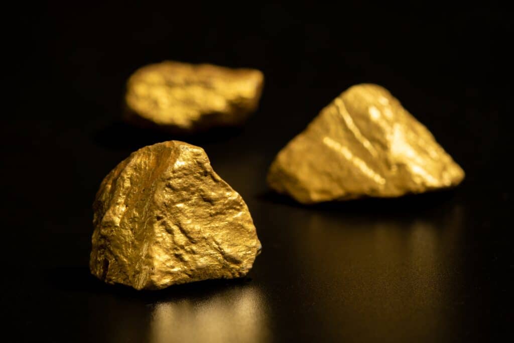 Pepite d'oro puro grezzo poggiate su una roccia, rappresentazione dell'oro da investimento estratto in natura